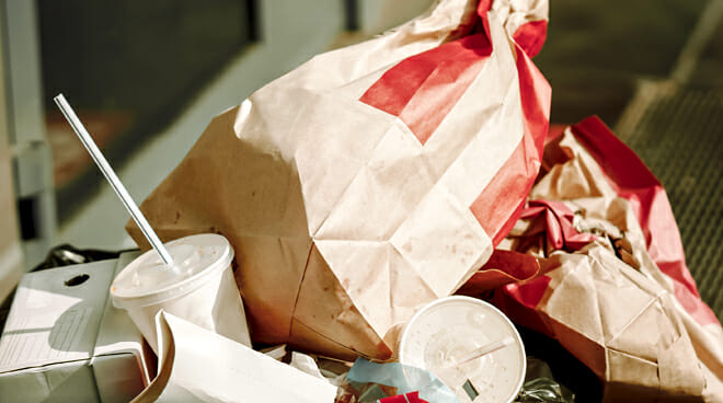 一个垃圾桶里装满了快餐包装和包装纸，这些食品可能含有新州规定禁止的PFAS化学品。